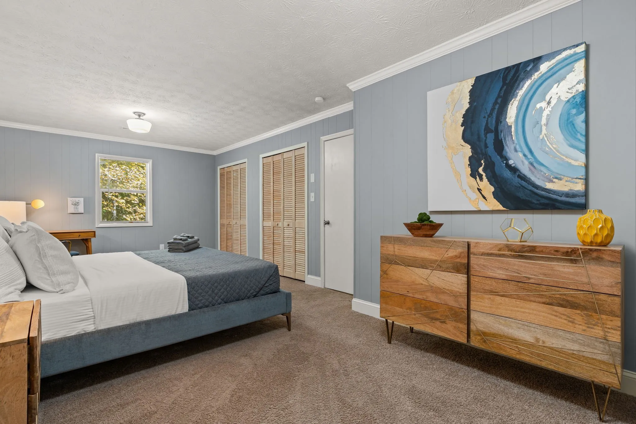 Bedroom with a blue accent wall and wood dresser